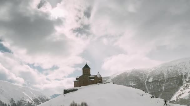 Stepantsminda, Gergeti, Georgia. Slavný kostel Gergeti Trojice Tsminda Sameba v zimní krajině — Stock video