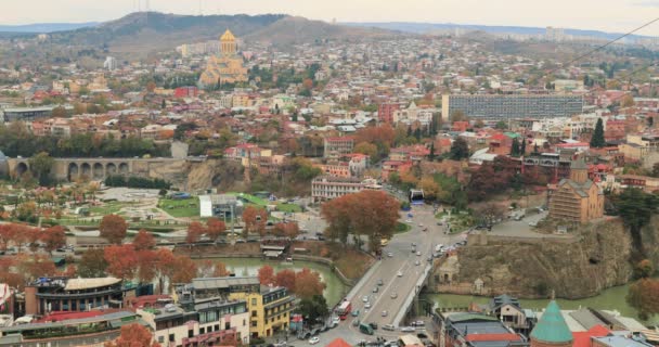 Tbilisi och Georgia. Ovanifrån berömda landmärken i höst kväll. Georgiens huvudstad Skyline Cityscape. Sameba kyrka, Rike Park och Metekhi kyrka. Linbana runt Kurafloden — Stockvideo