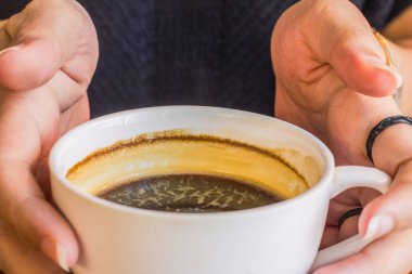 Bir kadının eli bir fincan kahve tutuyor..