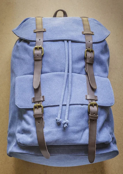 Blue backpack with leather elements on wood board background