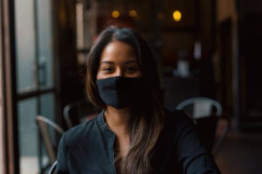 Kafede maske takan genç bir kadın. 