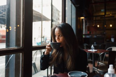 Genç melez kız kahve masasında oturuyor. 