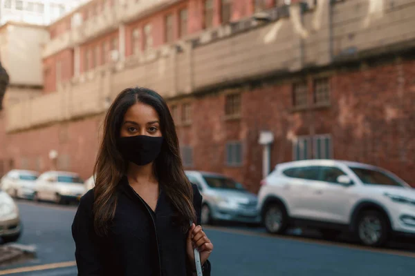街の路上で顔のマスクを身に着けている若い女性 ロイヤリティフリーのストック画像