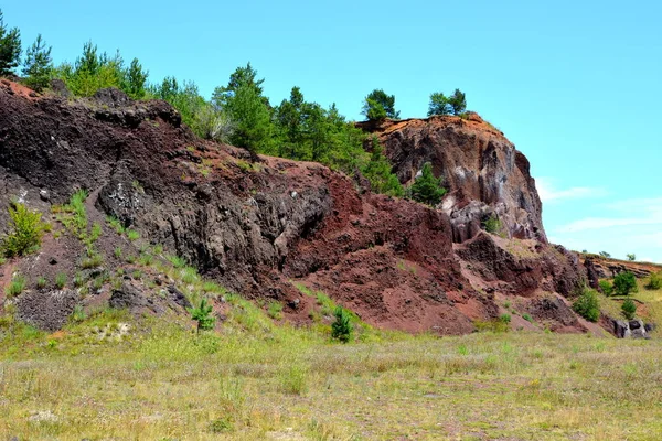 Abandoned career of red scorea rocks. Racos is a village in Brasov county, Transylvania, Romania near one active and three abandoned stone career. It is a national protected area