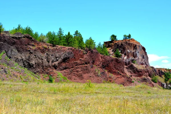 Abandoned career of red scorea rocks. Racos is a village in Brasov county, Transylvania, Romania near one active and three abandoned stone career. It is a national protected area