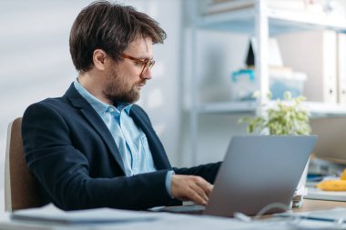 Genç işadamı dizüstü bilgisayarla çalışıyor.