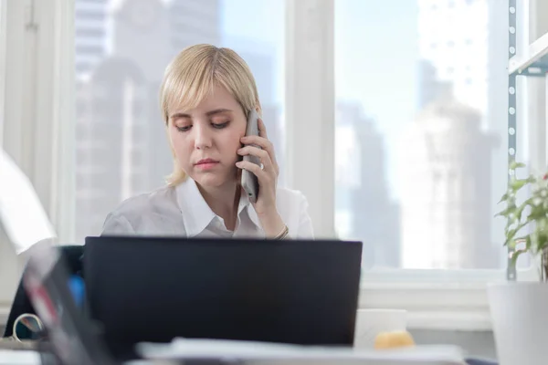 Junge Geschäftsfrau Spricht Mit Smartphone Und Arbeitet Laptop — Stockfoto