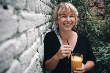 Bahçesinde portakal suyu içen güzel genç bir kadın.