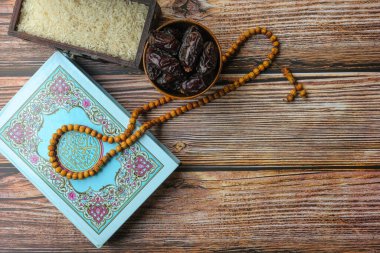 Kutsal Kur 'an, eski kutuda pirinç, ahşap zemin üzerinde hurmalar ve ahşap tespih. Zekat kavramı