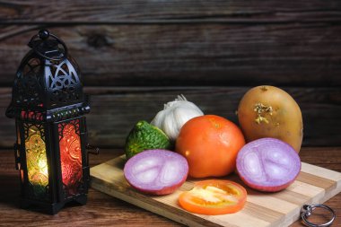 Tahta arka planda domates, sarımsak, kaffir limonu, soğan, patates ve fener. Yemek pişirme kavramı.