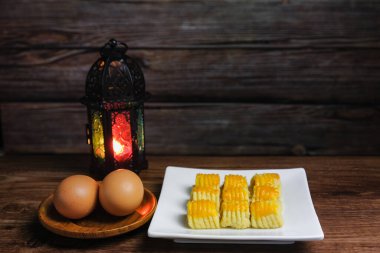 Malezya 'da Hari Raya Aidilfitri sırasında geleneksel atıştırmalıklara kuih tart ya da ananaslı tart ve ahşap arka planda yumurtalar deniyor..