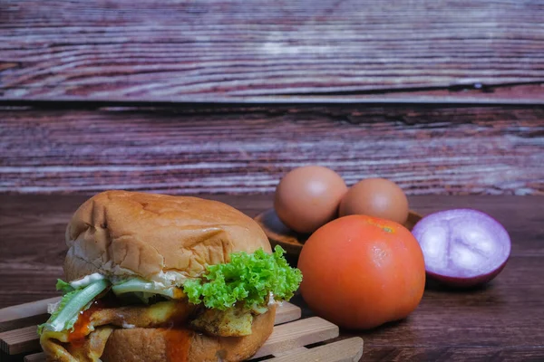 Egg burger , tomato, onion and eggs on wooden background