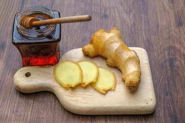 Ahşap arka planda küçük bir kavanoz bal ve zencefil..