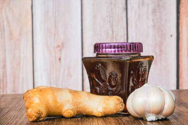 Small jar of honey and, garlic,    ginger  on wooden background.