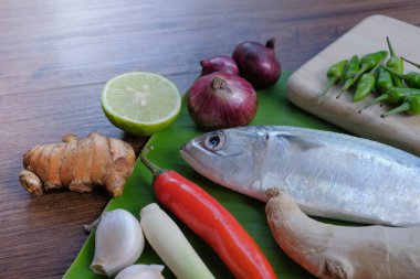 Ikan Pepes yapmak için baharatlı uskumru ya da ahşap masada muz yapraklarına sarılmış ızgara balık..