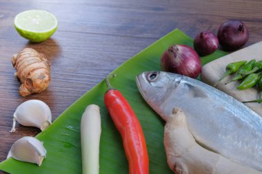 Ikan Pepes yapmak için baharatlı uskumru ya da ahşap masada muz yapraklarına sarılmış ızgara balık..