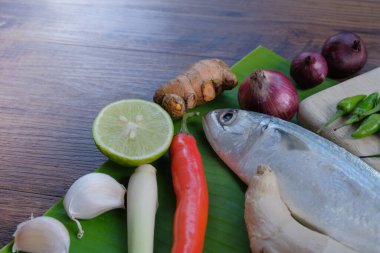 Ikan Pepes yapmak için baharatlı uskumru ya da ahşap masada muz yapraklarına sarılmış ızgara balık..