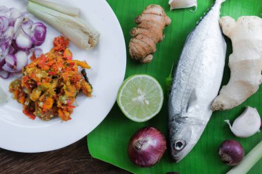 Ikan Pepes yapmak için baharatlı uskumru ya da ahşap masada muz yapraklarına sarılmış ızgara balık..