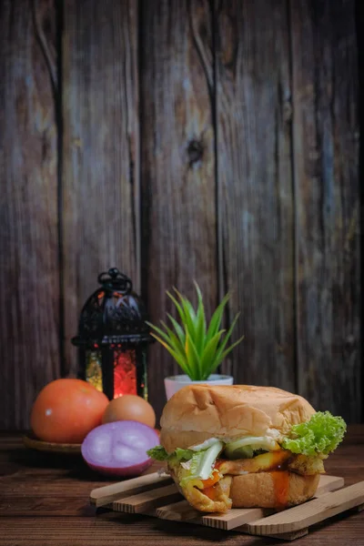 Egg burger, onion, eggs, tomato and lantern  on wooden background