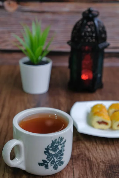 Traditional cookies in Malaysia during Hari Raya Festival known as Kuih tart or pineapples tart with lantern and tea  on the wooden background
