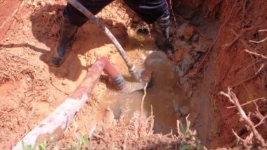 Erkek elektrik işçisi yeraltındaki bozuk su borusunu tamir ediyor..