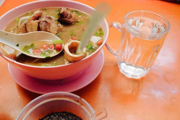 Bone marrow soup also known as soup gear box.served in a pink bowl. The glass contain word TAHAN PANAS or hot resistant