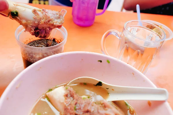 Bone marrow soup also known as soup gear box.served in a pink bowl. The glass contain word TAHAN PANAS or hot resistant