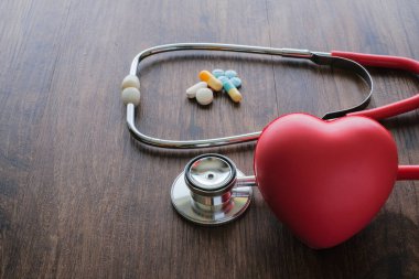 İlaç tabletleri, haplar, steteskop ve kırmızı kalp sağlık hizmetlerinden tıbbi geçmiş.