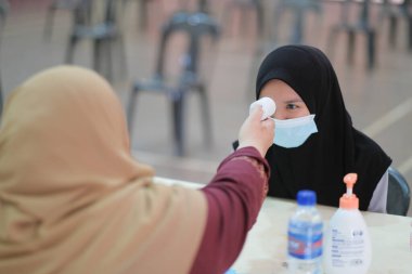 Öğretmen hararet için termometre sıcaklık tarama öğrencisini kullanıyor