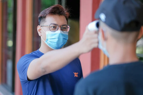 Öğretmen hararet için termometre sıcaklık tarama öğrencisini kullanıyor