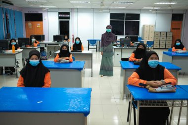 Muadzam Şah, Malezya - 29 Haziran 2020: Yeni Normal Kavram 'da sosyal uzaklık, Öğretmen, Oğlan ve Yüzü maskeli kız Sınıfta yaşıyor. Corona virüsü veya COVID-19 salgınını önle.