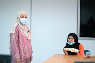 Muadzam Şah, Malezya - 25 Haziran 2020: Öğrenci sınıfta yemek yiyor. Sosyal uzaklık. Corona virüsünün veya covid-19 'un korunması kavramını kabul et.