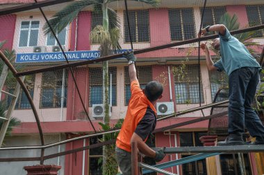 Muadzam Şah, Malezya - 7 Temmuz 2020: Çatı iskelesine başlamadan önce iki işçi iskeleyi birleştiriyor