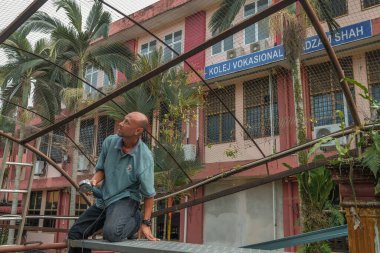 Muadzam Şah, Malezya - 7 Temmuz 2020: Metal çatı iskeleti kesmek için öğütme makinesi kullanan işçi