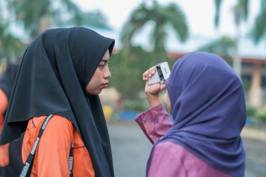 Muadzam Şah, Malezya - 9 Temmuz 2020: Öğretmen, COVID-19 yayılımına karşı termometre sıcaklığı ölçümleme öğrencisini kullanıyor..