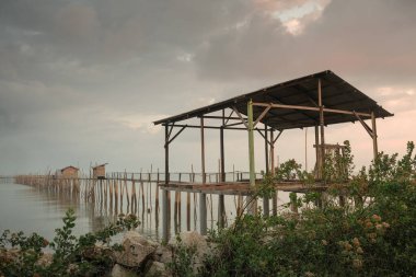 Langgai, arka plan olarak güzel bir gündoğumu olan Parit Jabar, Batu Pahat, Malezya 'da bambu ve ahşaptan yapılmıştır. Yumuşak odak, gürültü ve tahıl uzun süre maruz kalma.
