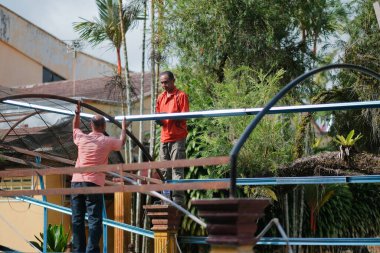 Muadzam Şah, Malezya - 15 Temmuz 2020: Kablosuz matkap ve vida kullanarak çatı için metal çatı işçiliği yapan inşaat işçileri. Endüstriyel kavram.