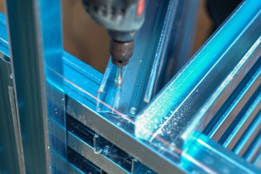 İnşaat işçisi inşaat alanında c kanalı çelik kirişleri takmak için elektrikli matkap ve vida aletleri kullanıyor. Endüstriyel kavram.