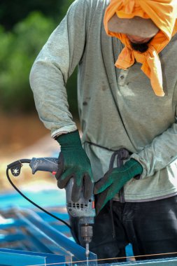 İnşaat işçisi inşaat alanında c kanalı çelik kirişleri takmak için elektrikli matkap ve vida aletleri kullanıyor. Endüstriyel kavram.