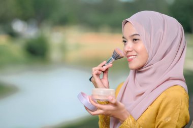 Asean kadın yüzüne makyaj yapıyor, geleneksel Malay elbisesi giyiyor..