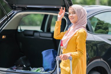 İş seyahatinde tesettürlü bir iş kadını bavulu bagaja koyar..