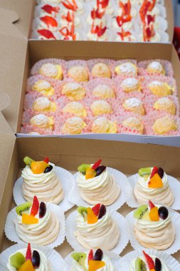 Krem şantili mini pavlovalar, karton kutuda taze meyve ve krema.