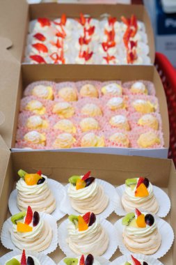 Krem şantili mini pavlovalar, karton kutuda taze meyve ve krema.