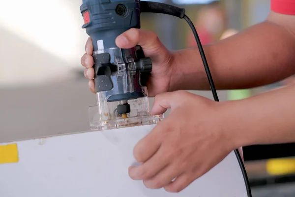 Genç marangoz kenar şeritleri kesmek için katmanlı budama makinesi kullanıyor. .