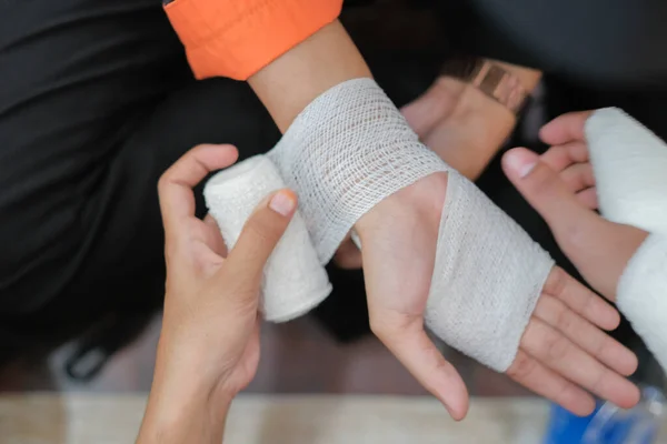 Öğrenci ilk yardım eğitimi koridorda. Üniversitede bir hastanın kırık elini elastik bandajla sabitlemeye çalışan bir öğrenci..