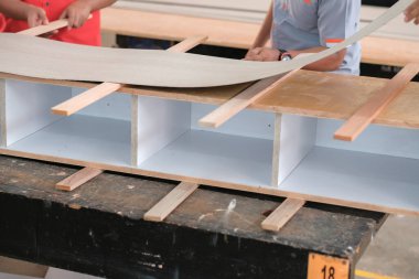 Marangoz, ev dekorasyonu için bir televizyon mobilyasına plastik bir tezgah kuruyor.