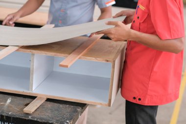 Marangoz, ev dekorasyonu için bir televizyon mobilyasına plastik bir tezgah kuruyor.