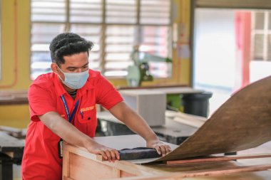 Muadzam Şah, Malezya - 1 Eylül 2020: Genç marangoz atölyelerdeki dolaplara plastik döşeme