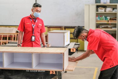 Muadzam Şah, Malezya - 1 Eylül 2020: Genç marangozlar atölyelerdeki dolaplara plastik döşüyorlar