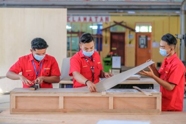 Muadzam Şah, Malezya - 1 Eylül 2020: Atölye atölyelerindeki dolaplara lamine döşeyen genç marangozlar